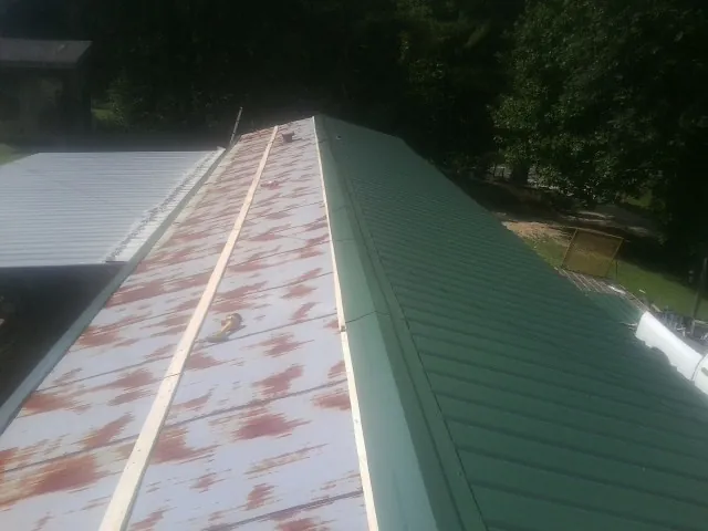 Old rusted panels beside newly installed green metal roofing — Wind Damage Roof Repair by Roofing Brothers in Glenn