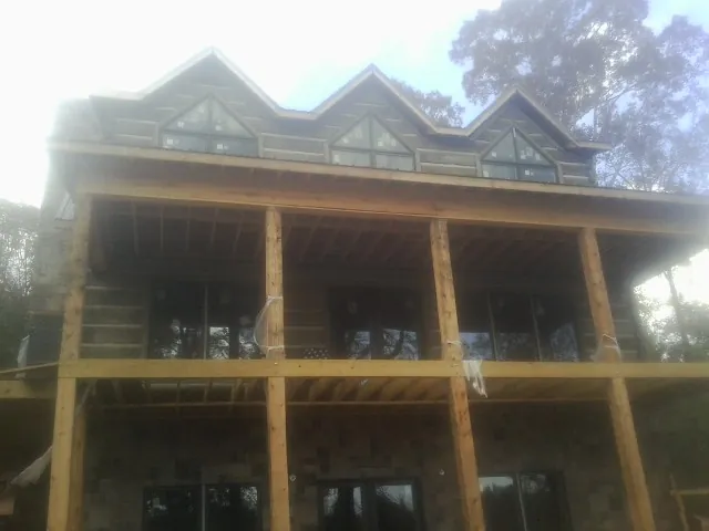 Dormers and porch framing on a large log home under construction — Roof Coating work by our crew in Glenn