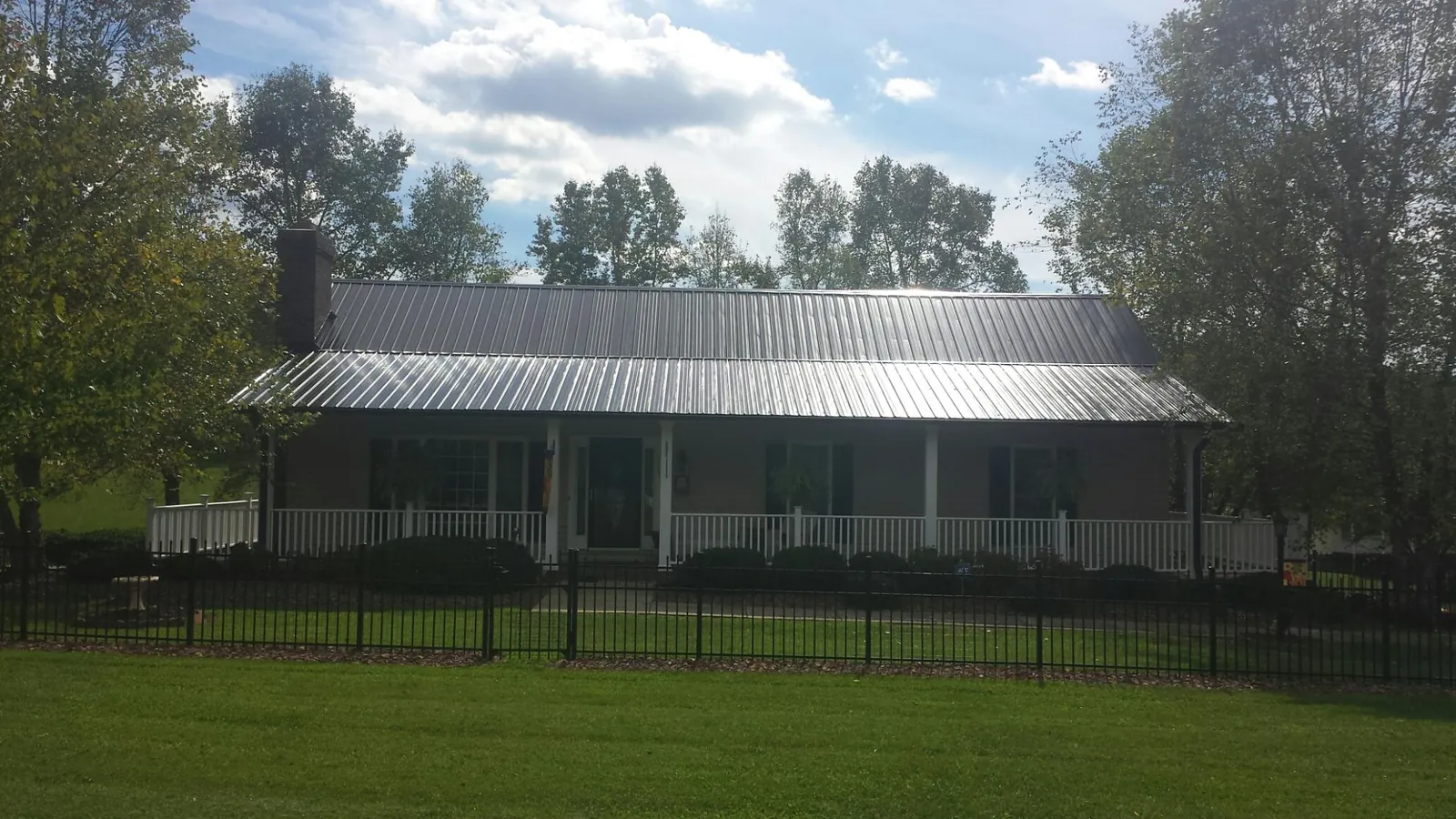 Gray metal roof on a brick ranch with a full width front porch — Gutter Guard Installation work by our crew in Glenn